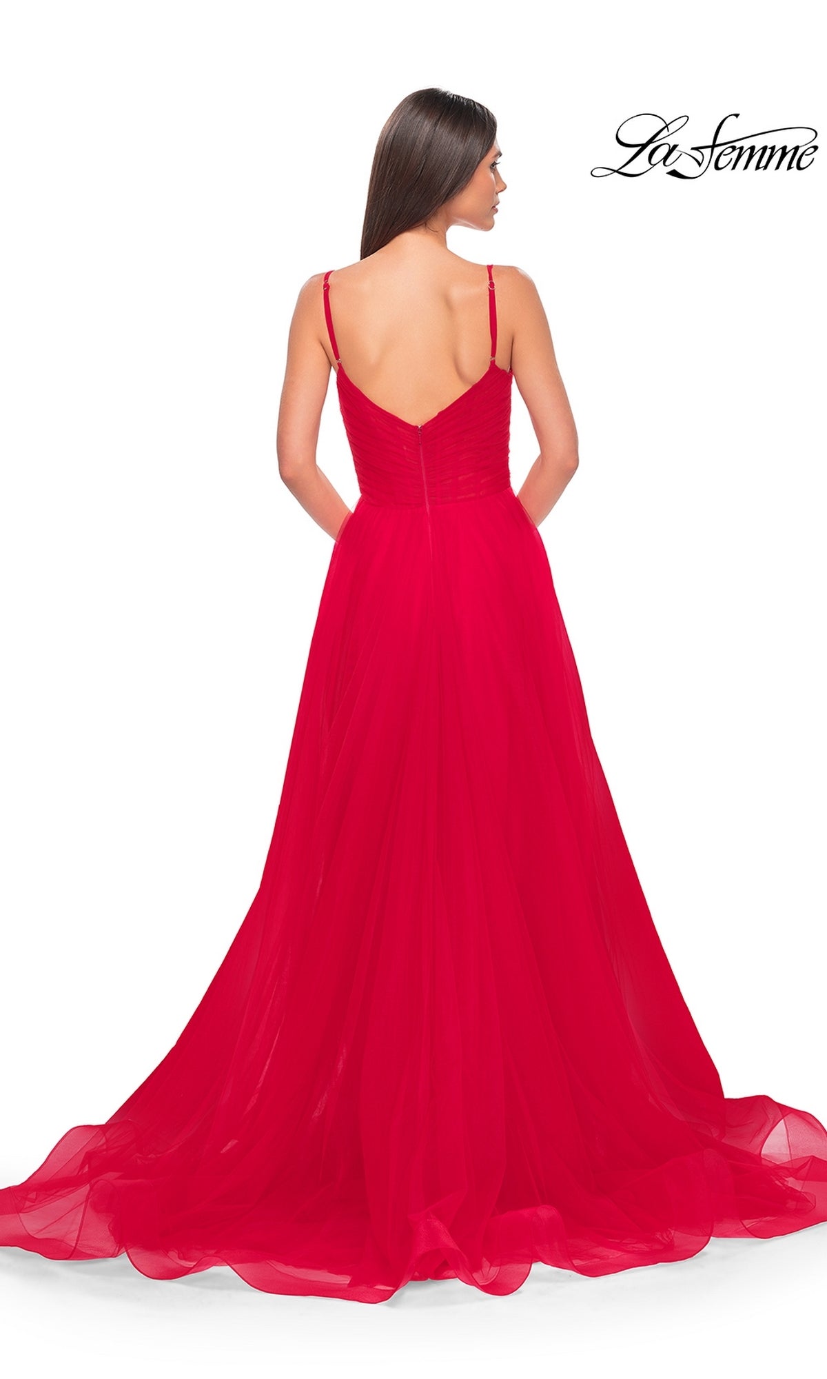 A woman with long brown hair models the La Femme Sheer-Waist Long A-Line Prom Dress 32130, a sleeveless, floor-length gown with thin straps and a V-back, set against a white background.