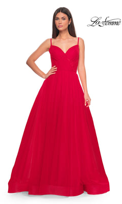 Woman wearing a La Femme Sheer-Waist Long A-Line Prom Dress 32130 in red, featuring thin straps and a fitted bodice, stands against a plain white background.
