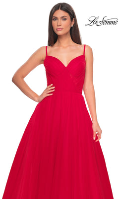 A woman wears the La Femme Sheer-Waist Long A-Line Prom Dress 32130—bright red, sleeveless, with thin straps, a fitted bodice, and flowing skirt. The "La Femme" logo appears in the top right corner.