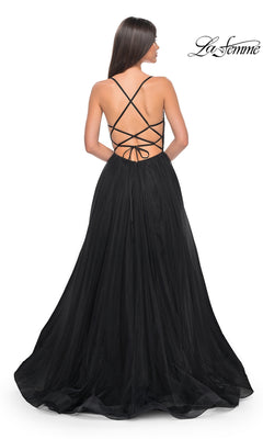 A woman stands facing away in the La Femme Embellished Long Tulle Prom Dress 32135, featuring a beaded bodice, crisscross lace-up straps, flowing floor-length skirt, and an elegant backless design.