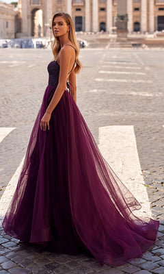 A woman wears the La Femme Embellished Long Tulle Prom Dress 32135, featuring a beaded bodice, as she stands on a cobblestone plaza with historic architecture in the background.