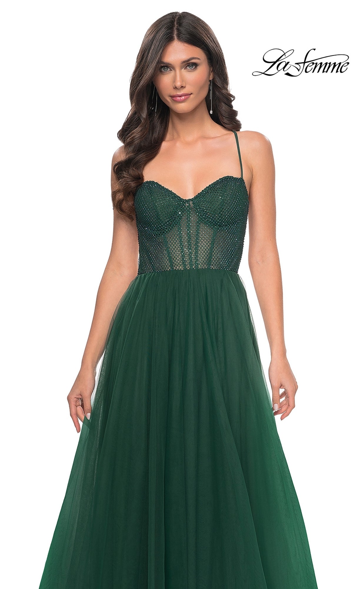 A woman wears the La Femme Embellished Long Tulle Prom Dress 32135, featuring a dark green mesh beaded bodice and a flowing A-line skirt, standing against a white background.