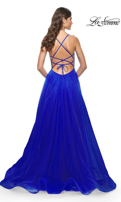 Woman in a royal blue La Femme Embellished Long Tulle Prom Dress 32135, featuring a beaded bodice, crisscross open back, and flowing skirt, stands with her back to the camera.