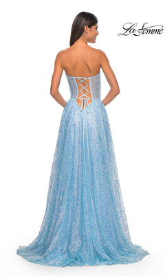 A woman stands with her back to the camera in the La Femme Strapless Embellished Prom Dress 32136, a glittery light blue A-line gown featuring a lace-up back, hot-stone accents for extra sparkle, and a slight train.