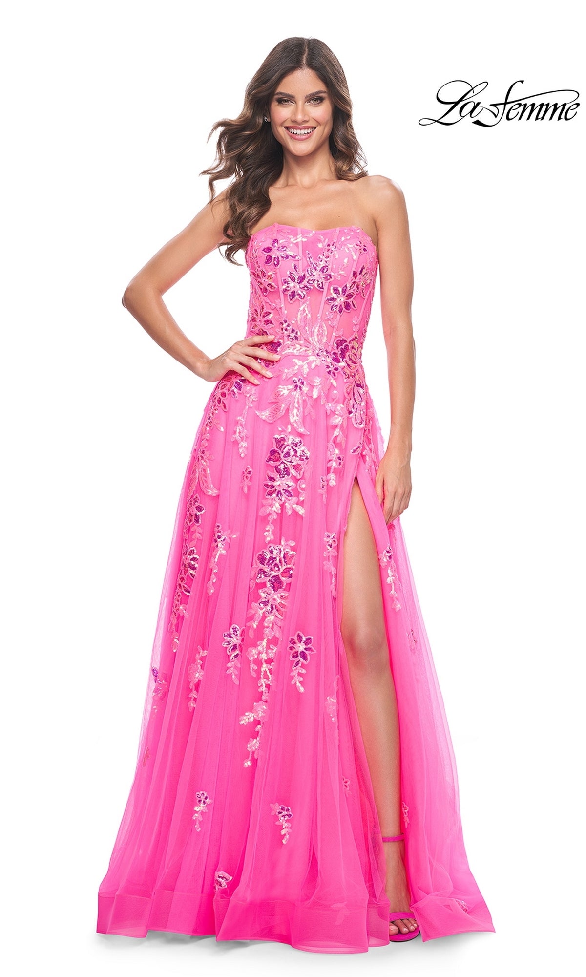 A woman smiles wearing the La Femme Neon Pink Long Prom Ball Gown 32137—a strapless formal dress with floral embroidery and a thigh-high slit. The La Femme logo is displayed in the top right corner.