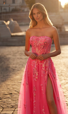 A woman stands outdoors on cobblestone pavement wearing the La Femme Neon Pink Long Prom Ball Gown 32137, featuring floral embroidery and a thigh-high slit.