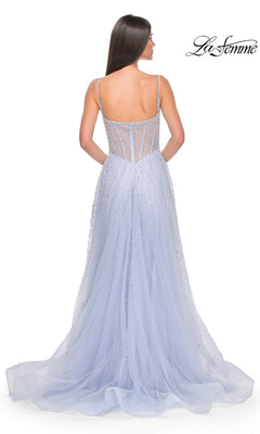 A woman stands with her back to the camera, wearing the La Femme Beaded Long A-Line Prom Dress 32146 in light blue, featuring delicate beading, thin straps, a sheer fitted bodice, and a flowing tulle train.