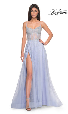 A woman in the La Femme Beaded Long A-Line Prom Dress 32146, featuring a light blue hue, spaghetti straps, a sheer bodice, and a high leg slit, stands with one hand on her hip.