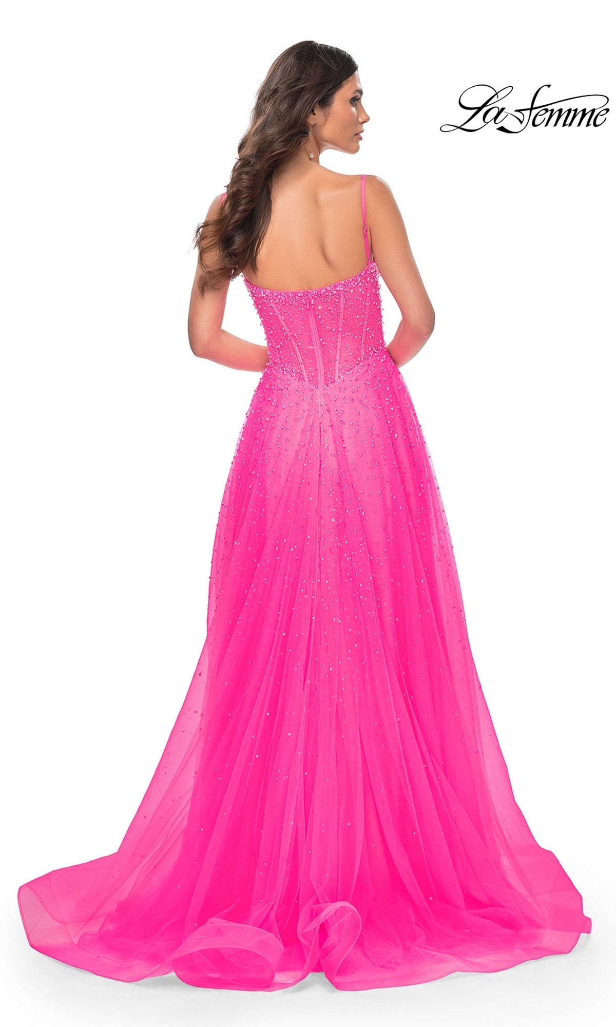 A woman models the La Femme Beaded Long A-Line Prom Dress 32146, a bright pink, floor-length gown with thin straps and beaded details, shown from the back. The 
