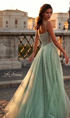 A woman in the sparkling seafoam green La Femme Beaded Long A-Line Prom Dress 32146 with thin straps stands on a stone bridge at sunset, glancing over her shoulder. The La Femme logo appears in the image.