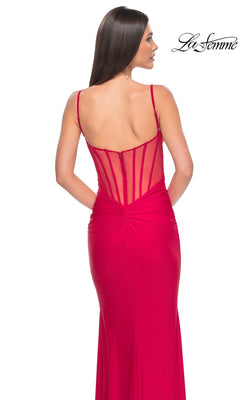 A woman models the La Femme Sheer-Back Long Jersey Prom Dress 32153 in fitted bright red with thin straps and a corset-style sheer back, posed against a white background. The "La Femme" logo is seen at the top right.