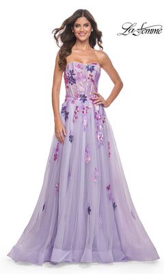 A woman smiles in the La Femme Strapless Long Lavender Prom Dress 32156, a floor-length gown with sequin flower embellishments. She stands against a plain white background with "La Femme" in the top right corner.