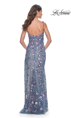 A woman with long wavy hair models the La Femme Blue Sequin-Print Long Prom Dress 32163, featuring sequin flower details and thin straps, photographed from the back. The La Femme logo is shown in the top right corner.