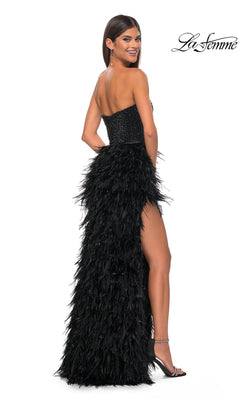A woman in the La Femme Feather Strapless Long Prom Dress 32165, featuring an embellished sweetheart bodice and feathered skirt, stands in high heels smiling over her shoulder. The La Femme logo appears in the top right corner.