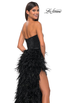 A woman models the La Femme Feather Strapless Long Prom Dress 32165, featuring an embellished sweetheart bodice and feathered skirt, as she smiles over her shoulder. The La Femme logo appears in the top right corner.