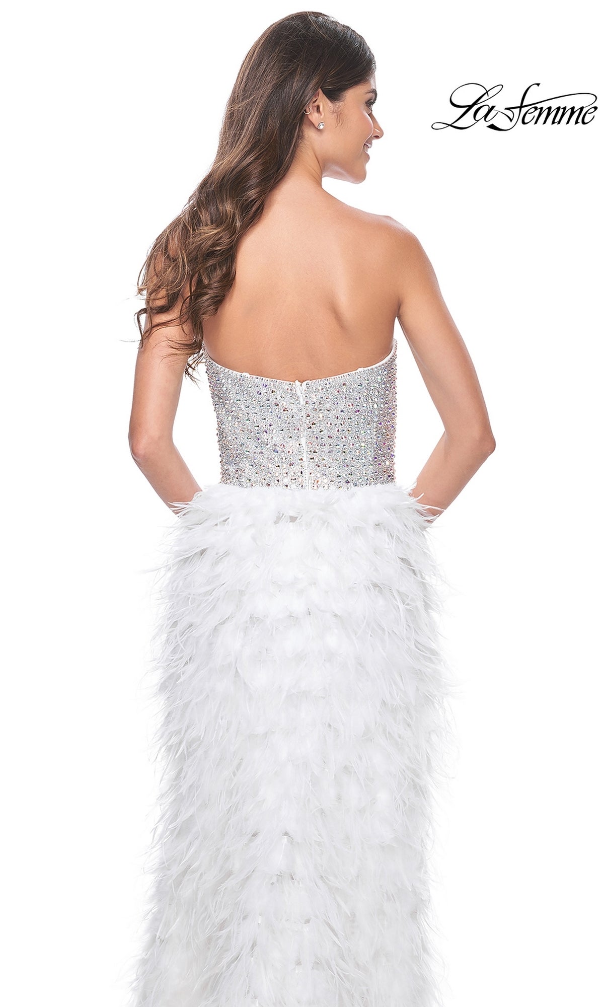 A woman faces away wearing the La Femme Feather Strapless Long Prom Dress 32165, featuring a sweetheart embellished bodice and a white feathered skirt; 