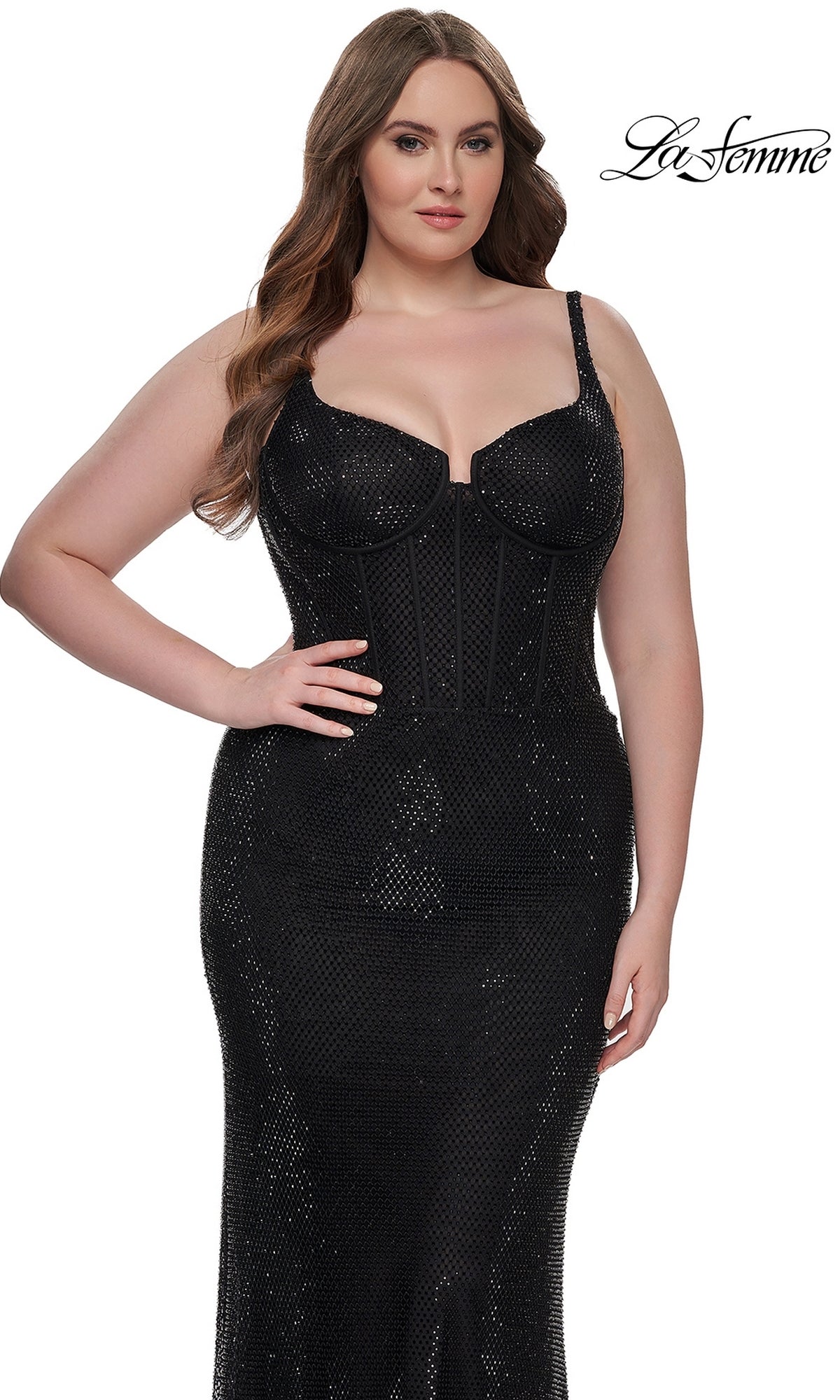 A woman in the La Femme Plus-Size Long Sequin Prom Dress 32189, featuring a fitted black design with thin straps and a structured bodice, stands before a white background with the La Femme logo.