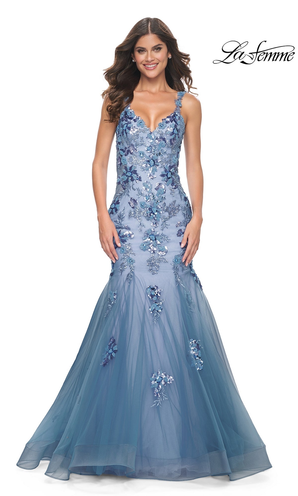Woman wearing the La Femme Slate Blue Long Mermaid Prom Dress 32192, featuring a fitted silhouette and elegant detailing, standing and smiling against a plain white background.