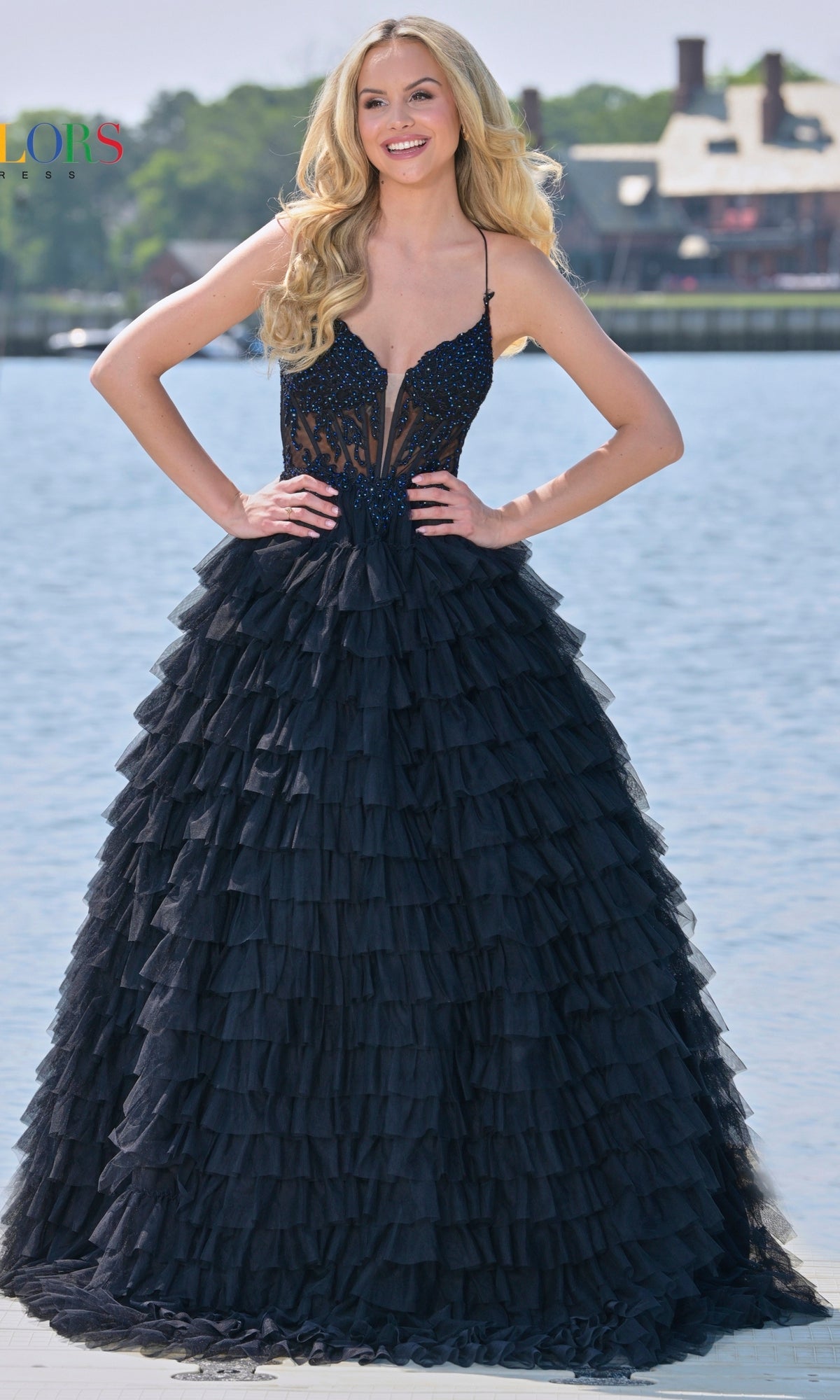 A woman smiles at the camera outdoors near water, wearing the Beaded-Corset Long Ruffled Prom Ball Gown 3219 with a fitted, embellished bodice.