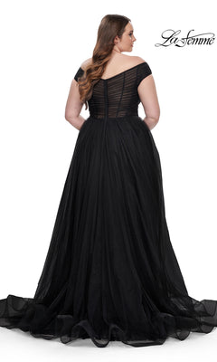 A woman wearing the La Femme Plus-Size Long A-Line Prom Dress 32204, featuring a black off-the-shoulder fitted sheer bodice, flowing tulle skirt, and dramatic train, stands facing away from the camera in this elegant designer gown.