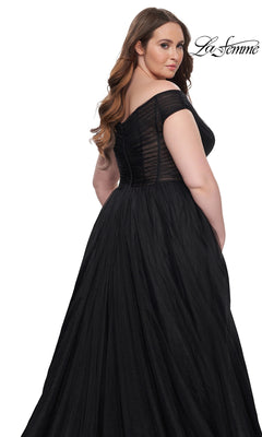 Woman models the La Femme Plus-Size Long A-Line Prom Dress 32204, a floor-length black off-the-shoulder gown with sheer bodice detailing, against a white background. "La Femme" logo appears in the top right corner.