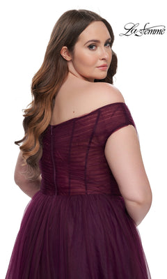 Plus-size model with long wavy hair in a burgundy off-the-shoulder La Femme A-line prom dress (style 32204), looking over her shoulder against a white background. "La Femme" logo appears in the top right corner.