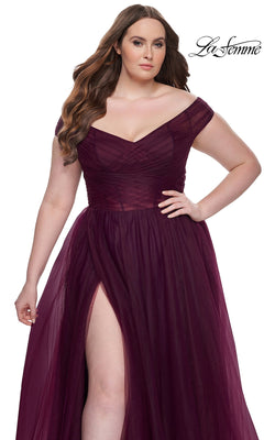 A woman wears the La Femme Plus-Size Long A-Line Prom Dress 32204 in deep burgundy, featuring an off-the-shoulder sweetheart neckline and thigh-high slit, standing against a white background with the La Femme logo in the top right corner.