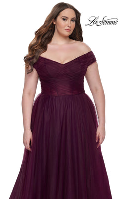 A woman models the La Femme Plus-Size Long A-Line Prom Dress 32204, featuring an off-the-shoulder fitted bodice and tulle skirt, against a white background. The La Femme logo appears in the corner to showcase this elegant gown.