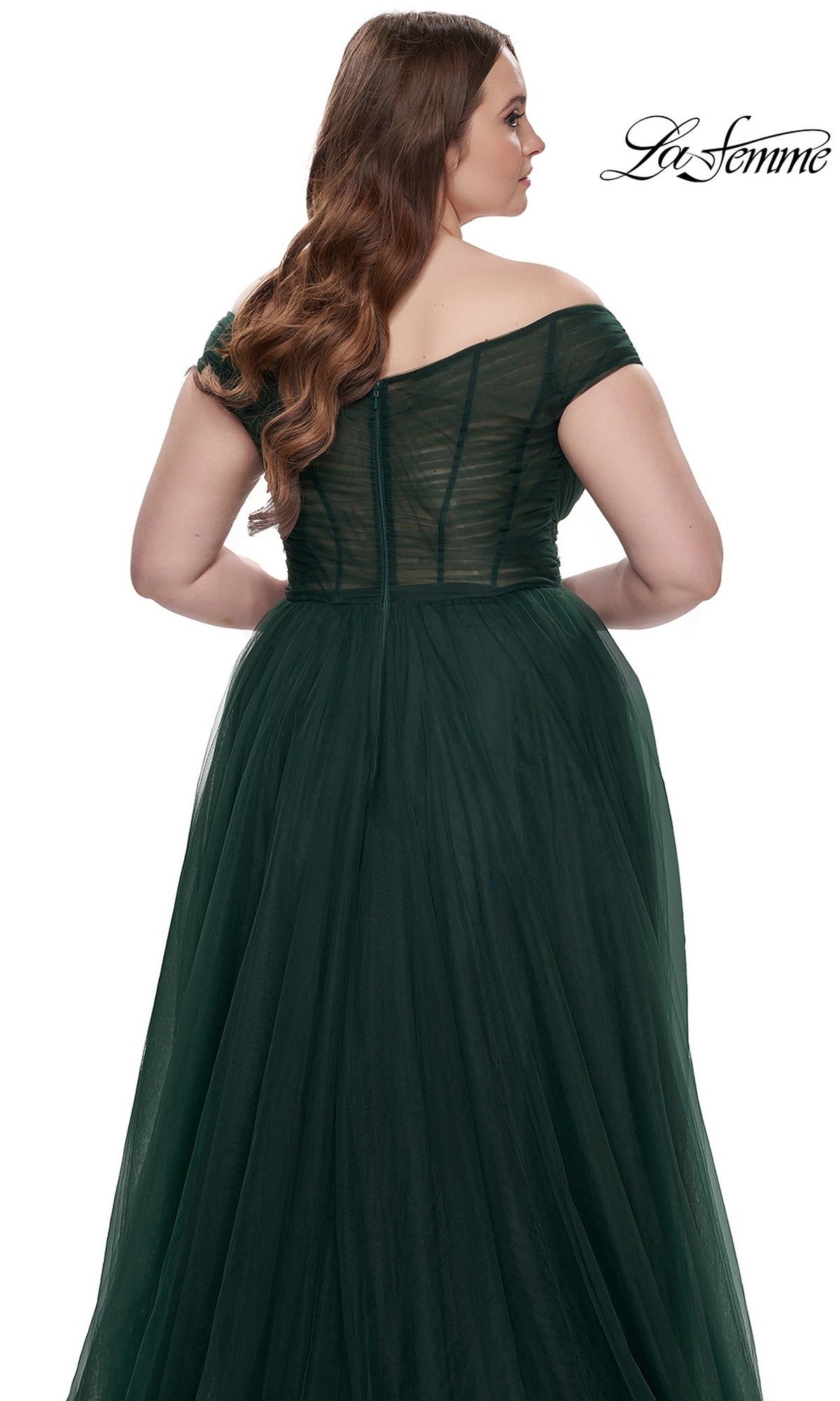 A woman is shown from the back wearing the La Femme Plus-Size Long A-Line Prom Dress 32204—an off-the-shoulder, dark green tulle gown with a fitted bodice, visible seams, and a full, flowing skirt.