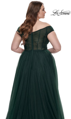 A woman is shown from the back wearing the La Femme Plus-Size Long A-Line Prom Dress 32204—an off-the-shoulder, dark green tulle gown with a fitted bodice, visible seams, and a full, flowing skirt.