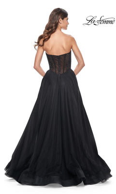 A woman stands with her back to the camera wearing the La Femme Strapless Long A-Line Prom Dress 32216 in black lace and tulle, featuring a fitted bodice and full skirt for an elegant formal look. The "La Femme" logo appears in the top right corner.