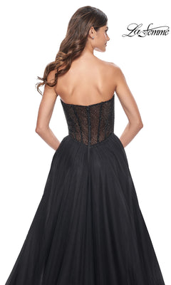A woman models the La Femme Strapless Long A-Line Prom Dress 32216, featuring a fitted textured bodice and full tulle skirt, shown from the back against a white background. This elegant formal gown offers timeless sophistication.