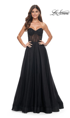Woman in the La Femme Strapless Long A-Line Prom Dress 32216, featuring a beaded semi-sheer bodice and flowing skirt, stands with hands on hips. "La Femme" logo appears in the top right corner.