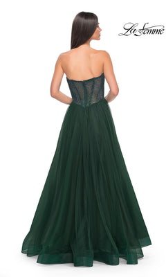A woman faces away against a white background in the La Femme Strapless Long A-Line Prom Dress 32216, featuring a fitted embellished bodice and dark green tulle skirt.
