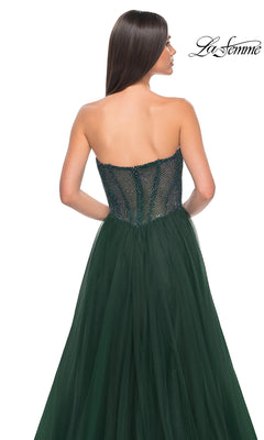 A woman with straight brown hair faces away, wearing the La Femme Strapless Long A-Line Prom Dress 32216 in dark green, featuring a sheer beaded bodice and tulle skirt. The "La Femme" brand appears in the top right corner.