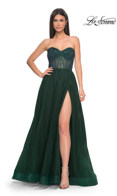 A woman stands against a white background wearing the La Femme Strapless Long A-Line Prom Dress 32216 in Dark Emerald, featuring a sheer beaded bodice and a thigh-high slit.