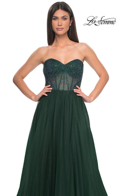 A woman poses against a white background in the La Femme Strapless Long A-Line Prom Dress 32216, dark green with a beaded semi-sheer bodice and tulle skirt.