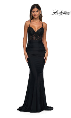 A woman wears the black Lace-Up Open-Back Long Prom Dress (La Femme 32217) with a fitted, floor-length silhouette and lace bodice, posing against a white background. The "La Femme" logo appears in the top right corner.