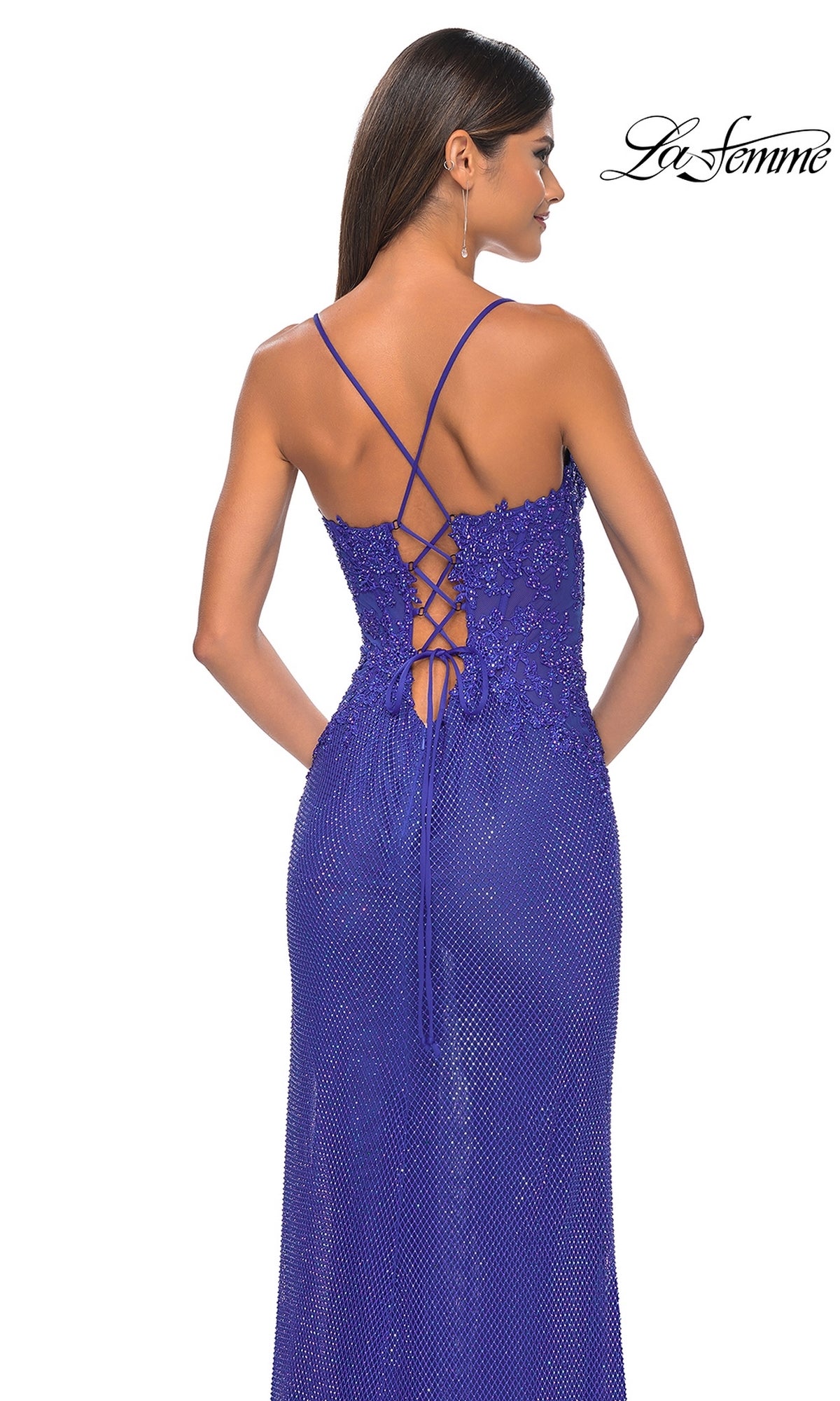 A woman in a purple La Femme Rhinestone Fishnet Long Prom Dress 32218 with thin straps and a lace-up back stands facing away from the camera. The La Femme logo appears in the top right corner.