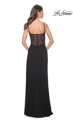 A woman faces away in the La Femme Sexy Long Black Prom Dress 32220, featuring thin straps, a sheer corset-style bodice, and a floor-length skirt. The "La Femme" logo appears at the top right.