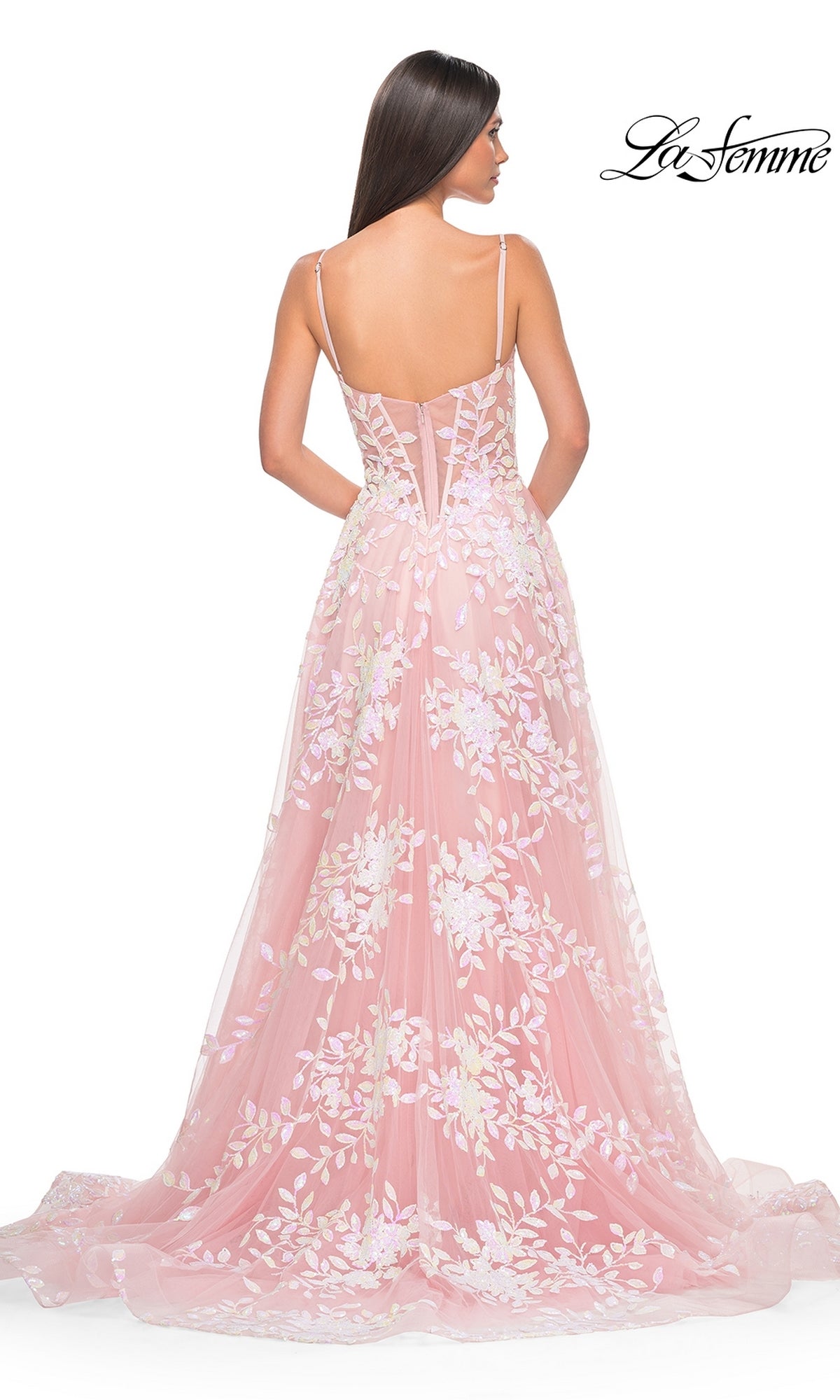 A woman in a pink, sequin-print La Femme Sequin-Print Long A-Line Prom Dress 32223 with spaghetti straps and a flowing skirt stands facing away. The 