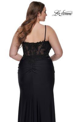 A woman wearing the La Femme Plus-Size Long Black Prom Dress 32226, featuring an embroidered-lace bodice and sheer details, stands with her back to the camera. The "La Femme" logo appears in the top right corner.
