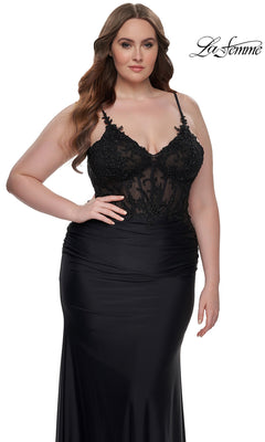 A woman models the La Femme Plus-Size Long Black Prom Dress 32226, featuring a sheer embroidered-lace bodice and thin straps, against a white background.