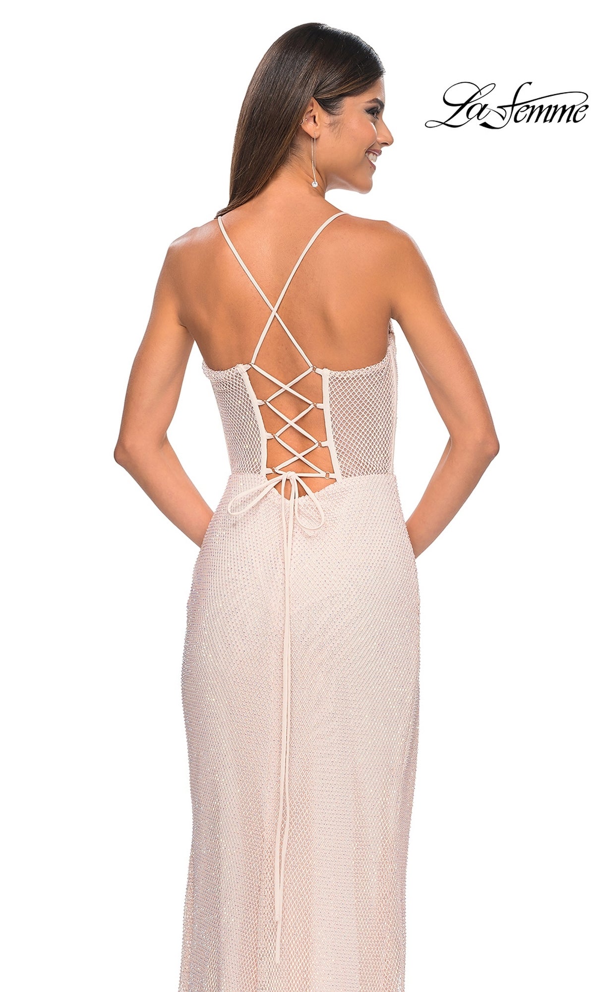 Woman in a sleeveless, light-colored La Femme Sheer Bustier Long Prom Dress 32227 with lace-up back and thin straps, standing against a white background. 
