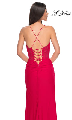 A woman is seen from behind wearing the La Femme Lace-Up Long Fishnet Prom Dress 32230 in red, featuring a floor-length design with thin crisscross straps, a lace-up back, and a sheer corset bodice.