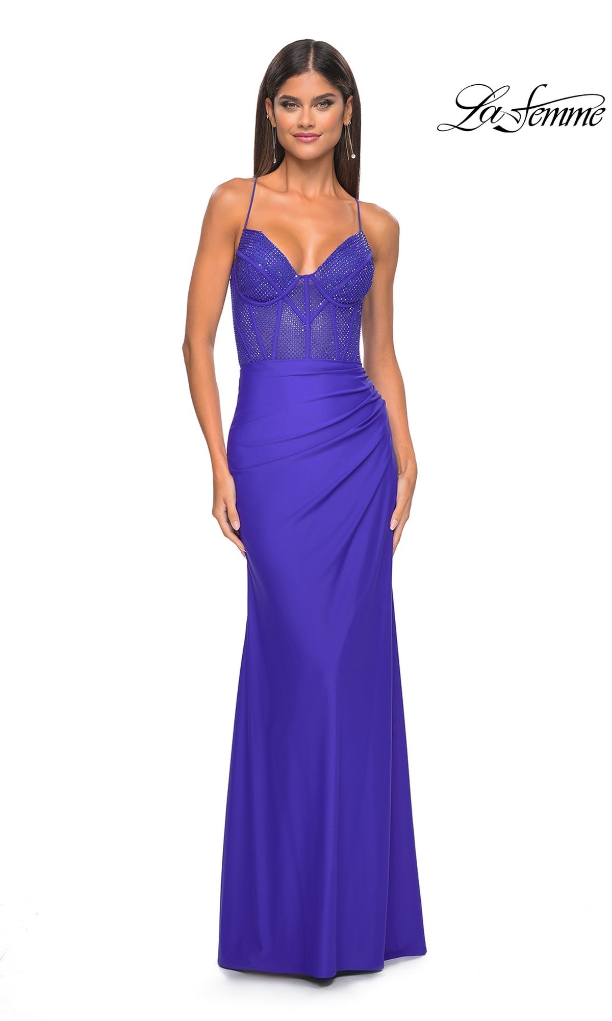 A woman wears a fitted, bright purple La Femme Lace-Up Long Fishnet Prom Dress 32230 with a beaded, semi-sheer corset bodice and thin straps, standing against a white background. The La Femme logo is in the top right corner.