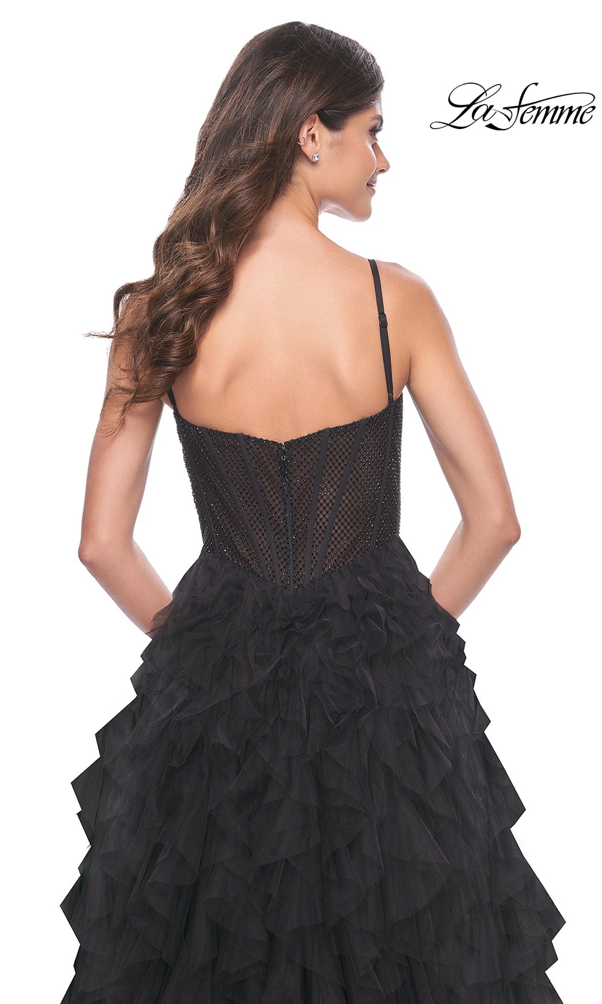 Woman in a black La Femme Sheer-Waist Long Ruffled Prom Dress 32233, strapless with a ruffled skirt, seen from the back against a white background.