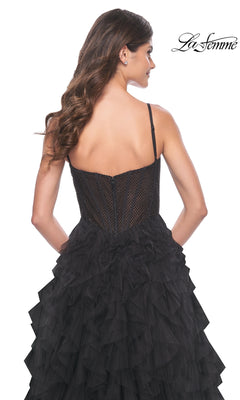 Woman in a black La Femme Sheer-Waist Long Ruffled Prom Dress 32233, strapless with a ruffled skirt, seen from the back against a white background.