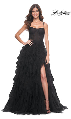 A woman wearing the La Femme Sheer-Waist Long Ruffled Prom Dress 32233 in black, featuring a corset-style bodice and thigh-high slit, stands smiling against a white background with the "La Femme" logo in the top right corner.