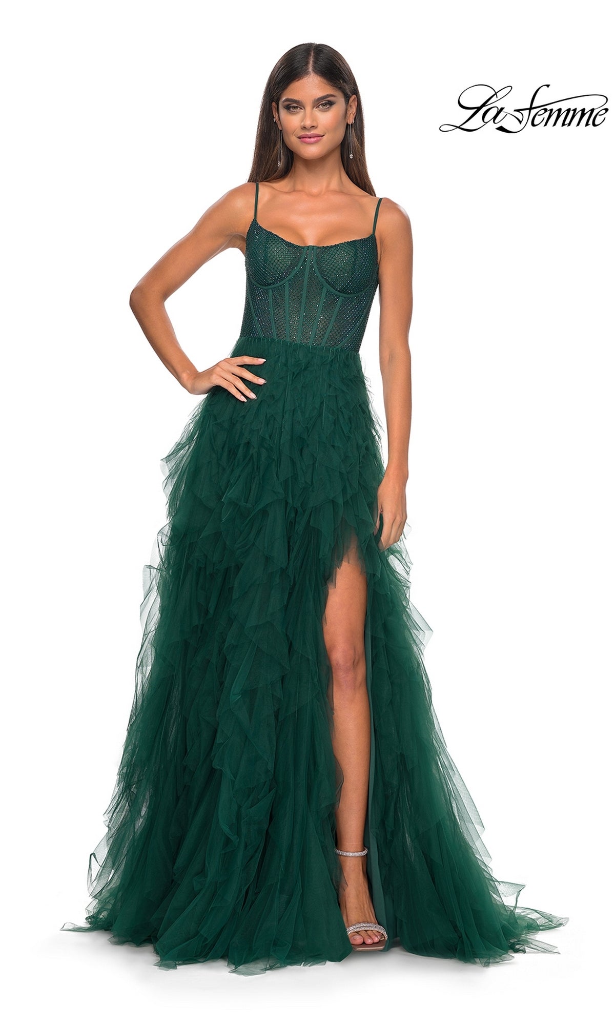 A woman wearing the La Femme Sheer-Waist Long Ruffled Prom Dress 32233 in Dark Emerald, featuring a sleeveless design, sheer corset bodice, beaded embellishments, a thigh-high slit, and a ruffled skirt.